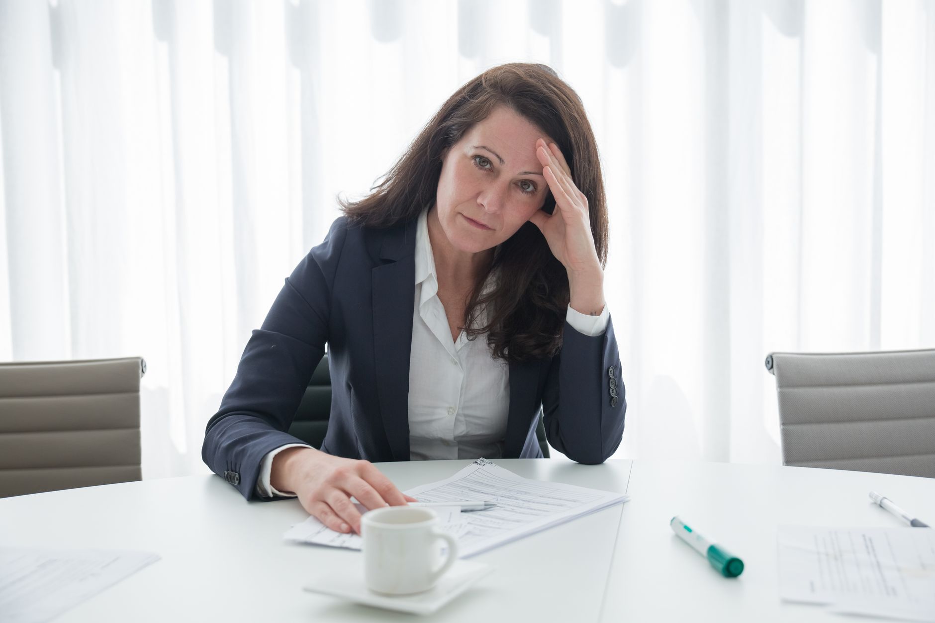 Zestresowana bizneswoman przy biurku z dokumentami, przytłoczona sytuacją